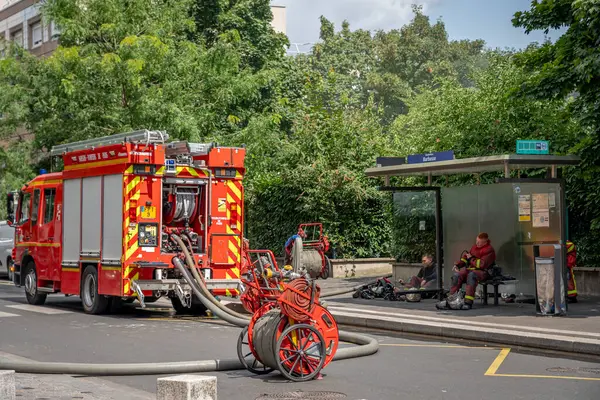 Gennevilliers, Fransa - 07 14 2025: Paris 'ten bir grup itfaiyeci ve kırmızı itfaiye aracı acil bir itfaiye söndürmeye hazırlanıyor