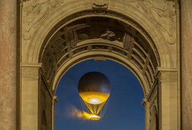 Paris, Fransa - 07 28 2025: Uçan Olimpiyat Kazanı 'na bakın Le Carrousel du Louvre' un ana kemerinden akşam üstü geçti.