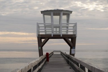 Gün doğumunda Balıkçı İskelesi adlı denizin önündeki ahşap iskeleye bakın.