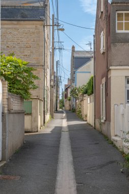 İskeleye ve sahile taş evlerin katıldığı dar bir geçit manzarası.