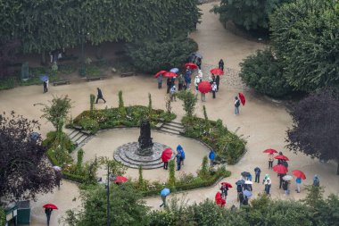Paris, Fransa - 09: 24 2025: Rene Viviani Meydanı 'nın panoramik manzarası ve Notre-Dame Katedrali De Paris' in kulelerinden yağan yağmur nedeniyle şemsiyeli insanlar