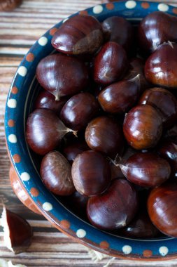 Kestaneler ahşap bir masada kasede. Dikey çekim. Yakın çekim..