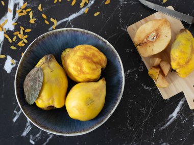 Karanlık sonbahar arka planında bir kasede taze sarı ayva meyvesi. En üst tablo görünümü.