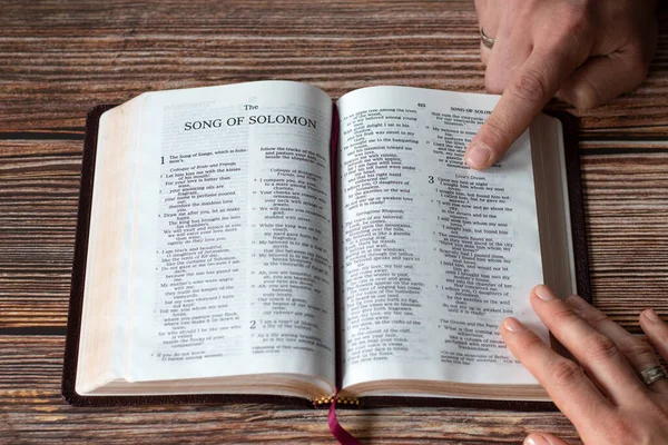 Hands of Christian couple holding Bible Book while reading together. Song of Solomon, old testament Scripture. The concept of love, prayer, studying biblical verses.