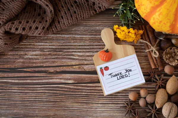 Thank You, LORD, handwritten text note on wooden background with pumpkin, nuts, and Bible Book. Copy space, Top table view. Autumn still life with a Christian thanksgiving card.