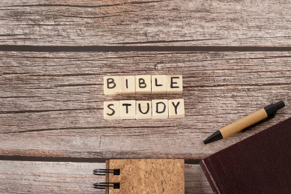 Bible study words on wooden cubes, notebook, Holy Bible Book, and pen on rustic background. Top table view. Christian education, learning, reading, writing Scriptures, biblical concept.