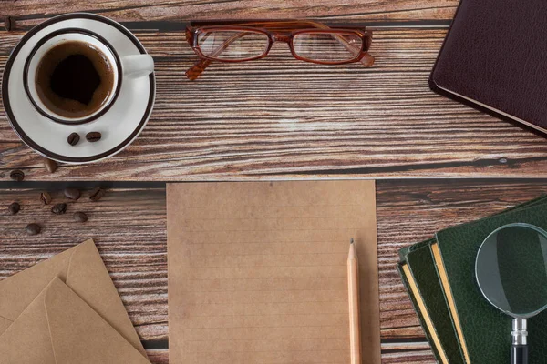 Bible Book, coffee cup, blank paper sheet, pencil, eyeglasses, and magnifying glass on wooden background. Top table view. Studying, writing, and searching Scriptures. Biblical concept.