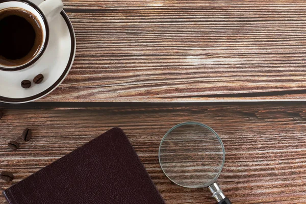 Holy Bible book, coffee cup, and magnifying glass on wooden background with copy space. Top table view. Studying, reading, and searching Christian Scriptures. Biblical concept.