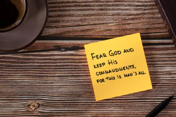 stock image Fear God and keep His commandments, handwritten verse on yellow note with bible book and coffee cup on wooden table. Top view. Christian biblical concept of obedience, faith, and hope in the LORD.