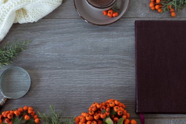 İncil kitabı, kahve fincanı, büyüteç, yün atkı ve ahşap masada kırmızı böğürtlen bitkisi. Uzayı kopyala, üst görünüm. Kışın ve sonbahar mevsiminde evde Hıristiyanlık eğitimi.