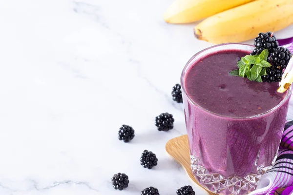 Beyaz arka planda taze nane aromalı böğürtlen muzlu smoothie. Uzayı kopyala Kahvaltıda dondurulmuş böğürtlenle karıştırılmış sağlıklı bir içecek..