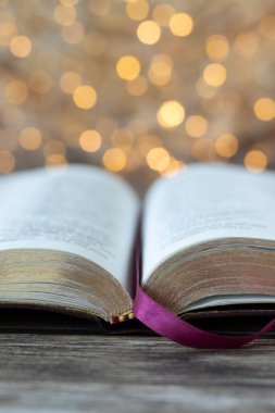 Kutsal İncil 'i altın arkaplanlı ahşap masanın üzerinde aç. Yakın plan. Dikey çekim. Seçici odaklanma. Hıristiyan Kutsal Kitap kavramı öğrenimi.