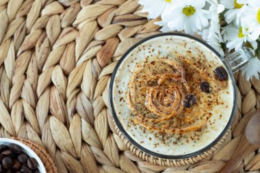 Kremalı kahve kremalı chia tohumu pudingi kırsal rattan masasında, çiçekli ve tahta kaşıklı. Üst görünüm, boşluğu kopyala. Sağlıklı, temiz vejetaryen kahvaltısı ya da tatlı..