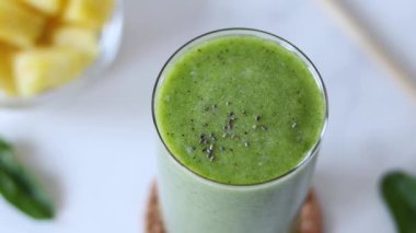 Yeşil detoks smoothie üzerine el serpme chia tohumu. Yakın plan. Kahvaltı için sağlıklı bitkisel meyve suyu hazırlama.