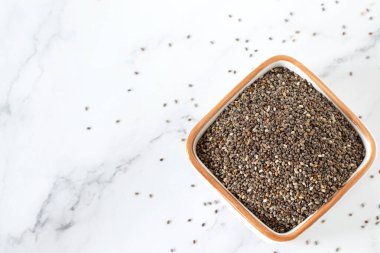 Beyaz mermer zemin üzerinde izole Chia tohumları kasede. Üst tablo görünümü, kopyalama alanı. Vegan proteini, omega 3 sağlıklı yağ yiyeceği..