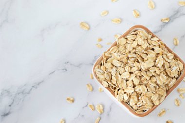 Yuvarlak yulaf ezmesi (çiğ yulaf gevreği) beyaz mermer arka planda izole edilmiş. Üst görünüm, alanı kopyala.