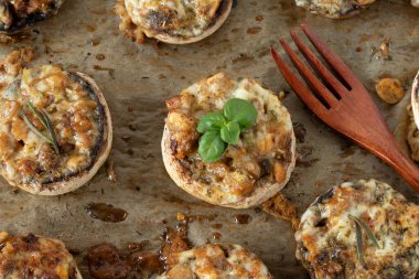 Eritilmiş peynirle doldurulmuş mantar ve ahşap çatalla pişirme tepsisinde baharat. Üst görünüm.