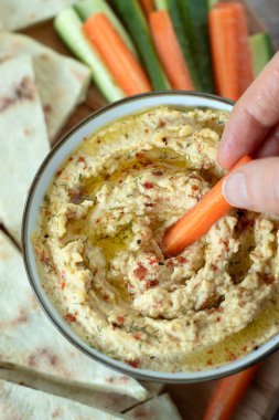 Ev yapımı nohut kasesine kırmızı biber parçacıkları serpiştirilmiş havuç çubuğu. Sağlıklı atıştırma konsepti. Üst görünüm.