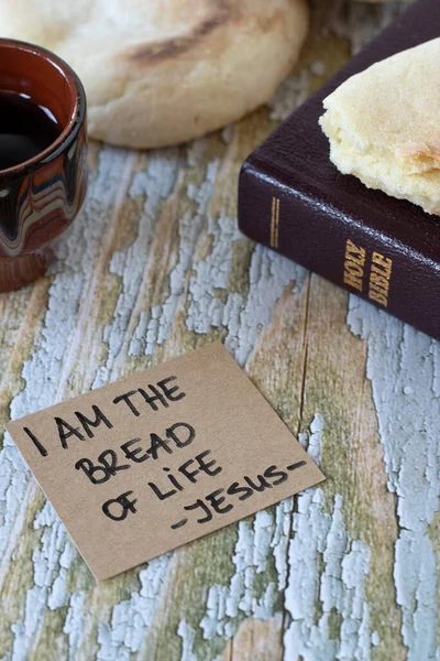 I am the bread of life-Jesus Christ, handwritten text with holy bible book and cup of wine on wood. Christian Passover, spiritual food and drink, salvation from God, biblical concepts.