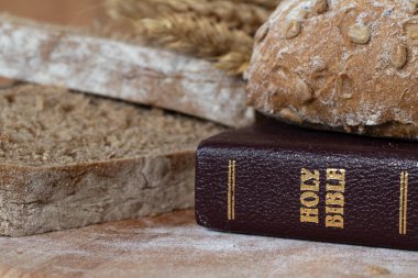 Kutsal İncil, somun ekmek ve buğday, ahşap masada. Yakın plan. İncil 'de geçen dini yemek kavramı.