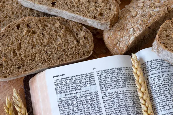 Whole grain bread and wheat with open holy bible book on wood. Top table view. Eating spiritual food, New Testament covenant, Christian biblical concept.
