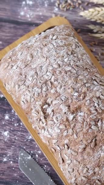 用芝麻籽和小麦粉在木制切菜板上烤的面包 顶级的桌面图 垂直录像 — 图库视频影像
