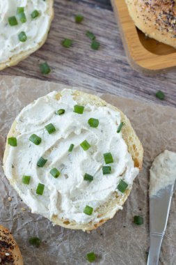 Krem peynirli bagel sandviç ve kahvaltıda taze soğan. Üst masa manzaralı. Sağlıklı gıda konsepti yemek..