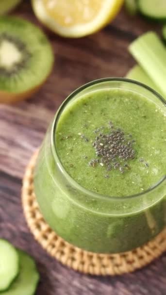 用奇亚种子 鳄梨和猕猴桃在木制桌子上的玻璃杯中制成绿色的排毒软糖 垂直录像 为早餐重新提供健康的混合饮料 — 图库视频影像