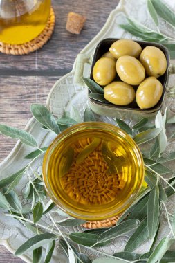 Ekstra saf zeytinyağı ve kırsal ahşap masada dalları olan yeşil zeytinler. Üst Manzara. Doğal organik Akdeniz yemekleri.