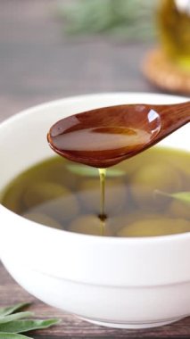 Tahta kaşıktan damlayan ekstra saf zeytinyağı. Dikey video. Yakın plan..