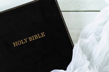 Kapalı kutsal kitap üzerindeki beyaz peçe. Üst masa manzaralı. Hıristiyan İncili kavramı.