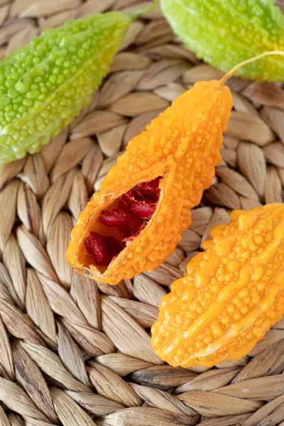 stock image Ripe karela (bitter melon, Momordica charantia) with orange and green color on bamboo table. Top view. Organic fresh tropical fruit.