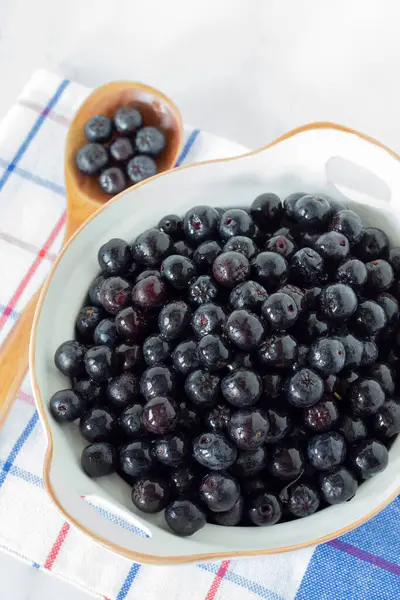 Beyaz mutfak masasındaki bir kasede olgun boğma böğürtlenleri (Aronia). Yakın plan..