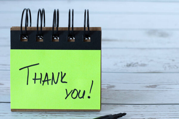 Спасибо, рукописная цитата на зеленой бумаге на деревянном столе. Крупный план. Концепция благодарения, благодарности и признательности.