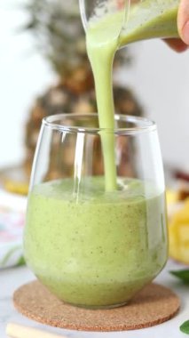 Ananas meyveli yeşil smoothie ve ıspanağı bardağa dolduruyorum. Dikey video. Yakın plan. Sağlıklı karışım, ferahlatıcı detoks suyu..