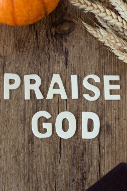 Praise God wooden text on rustic background with pumpkin, wheat, and holy bible book. Top view. Christian biblical concept. clipart