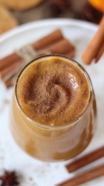 Tarçın çubuğu ve anason yıldız baharatıyla balkabağı içeceği süslemek. Dikey video. Yakın plan. Kremalı ev yapımı sonbahar smoothie.