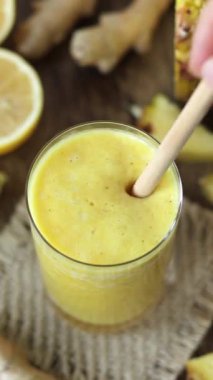 El, sarı ananaslı zencefilli limonlu içeceği taze nane ile karıştırıp dekore ediyor. Dikey video. Sağlıklı ev yapımı karışımı..