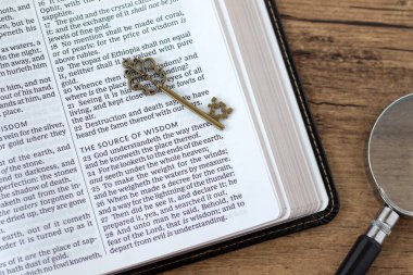 Tanrı 'dan gelen bilgelik kutsal kitaplarda yazılı antik anahtar ve ahşap masada büyüteç. Üst Manzara. İncil bilgisi, eğitim ve öğrenim, Hıristiyan konsepti.