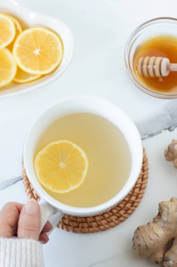 Zencefil kökü ve beyaz mermer masada ballı limon çayı fincanı. Üst Manzara. Sağlıklı ev yapımı sıcak içecek..