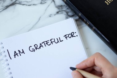 Minnettarlık için el yazısıyla yazılmış beyaz mermer masanın üzerinde kutsal İncil kitabı olan defteri aç. Üst Manzara. Günlükteki nimetler için İsa Mesih 'e şükran günü.