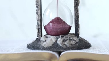 Kutsal İncil 'in beyaz arkaplanlı kum saati. Yakın plan. Zaman ve sabır, Hristiyan İncil kavramı.