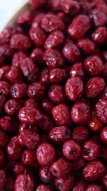 Kırmızı Çin hurmaları (jujube) beyaz arka planda bir tabakta dönüyorlar. Dikey video. Üst görünüm.