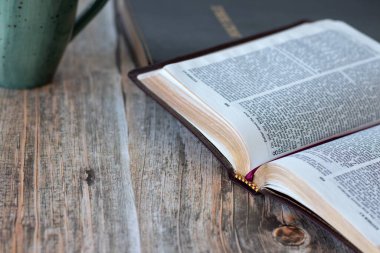 Hristiyan kutsal kitabı, üzerinde bir fincan kahve olan ahşap masa. Uzayı kopyala İncil eğitimi ve eğitim, İncil kavramı.
