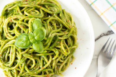 Beyaz mermer masada ıspanaklı, fesleğenli ve vegan parmesan peynirli yeşil spagetti. Üst Manzara. Yakın plan. Sağlıklı ev yapımı makarna..