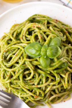 Yeşil makarna soslu vejetaryen spagetti fesleğenli ve çatallı parmesan peynirli. Üst Manzara. Yakın plan. Sağlıklı ev yapımı konforlu gıda.