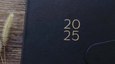 2025 yılbaşı not defteri planlayıcısı ve ahşap masa üzerinde bir fincan kahve. Üst Manzara. Yakın plan..