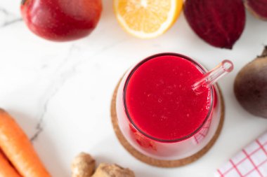 Kırmızı pancar suyu, zencefil, havuç, limon ve beyaz mutfak masasında elma suyu. Üst görünüm.