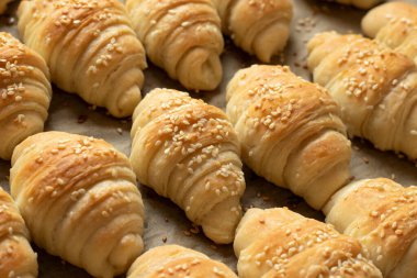 Tavada susam tohumları olan taze pişmiş hilal ruloları. Yakın plan..