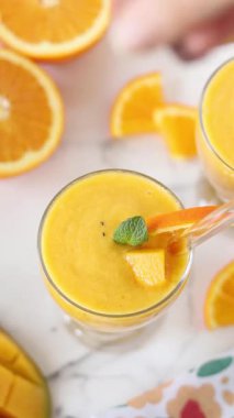 El mango portakallı smoothie 'nin üzerine chia tohumu serpiyor. Dikey video.
